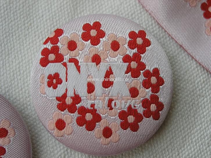 Tin badge wrapped by embroidered fabric